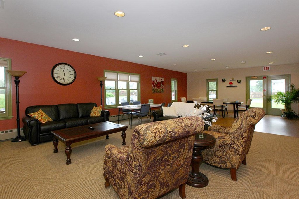 a living room with couches and chairs and a clock on the wall