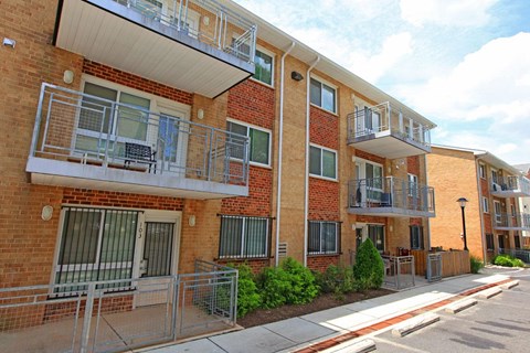 a brick apartment building with two balconies and a sidewalk