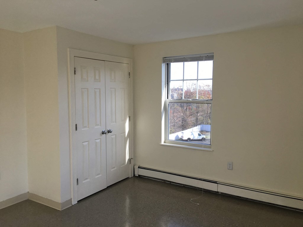an empty room with a window and a white door