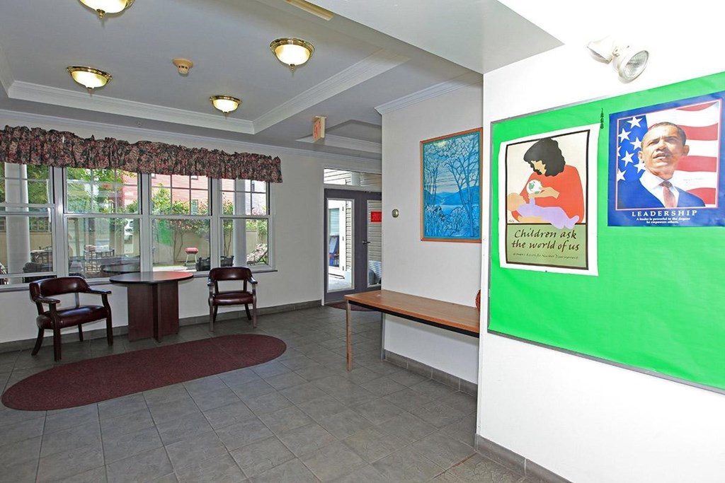 a lobby with tables and chairs and a green poster on the wall
