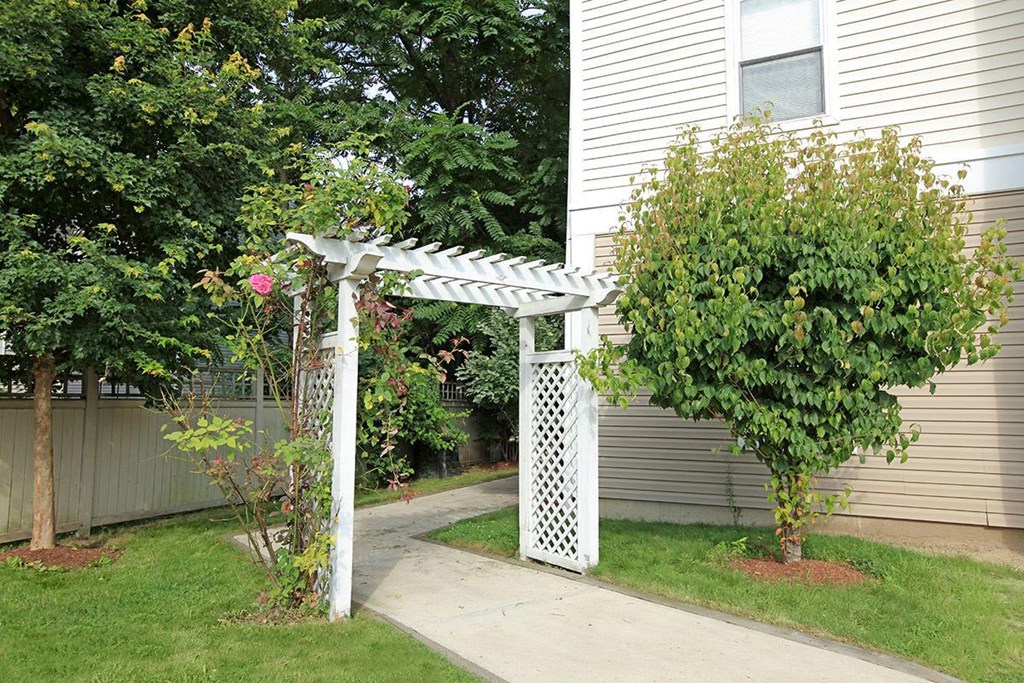 a white arbor in a yard next to a house