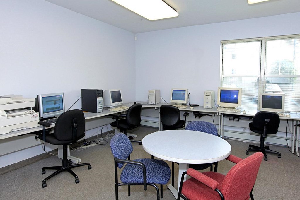 a classroom with computers and a table and chairs