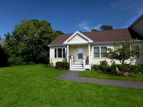 a small white house with a sidewalk in front of it