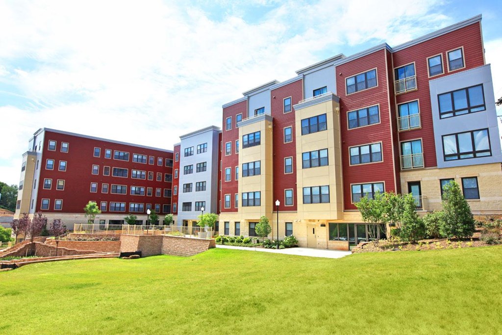 the exterior of an apartment building with a green lawn