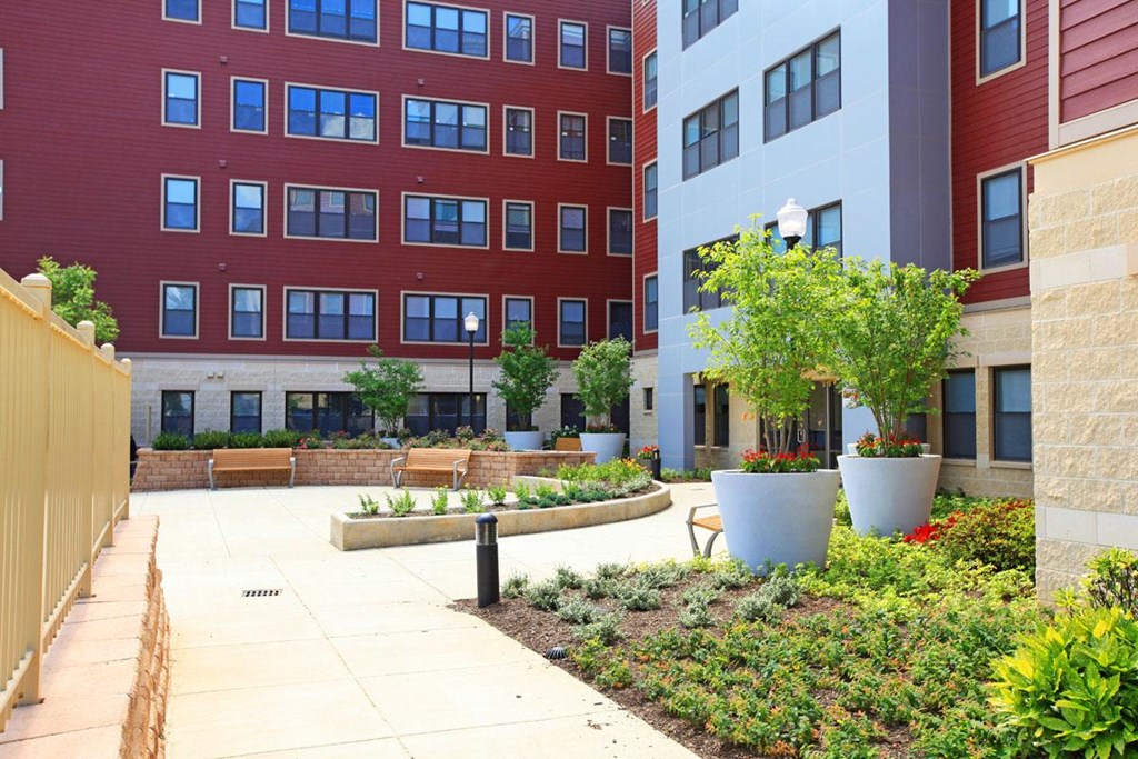 a courtyard with benches and plants in front of a building