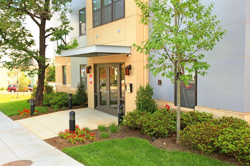 the front entrance of a building with a sidewalk and grass