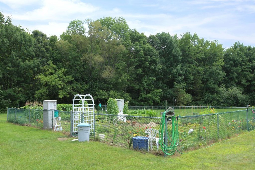 a garden with a fence and some trash cans
