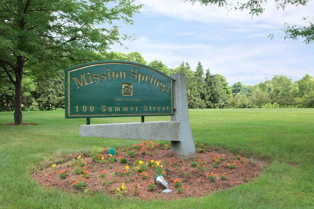 a sign for themission springs park with flowers around it