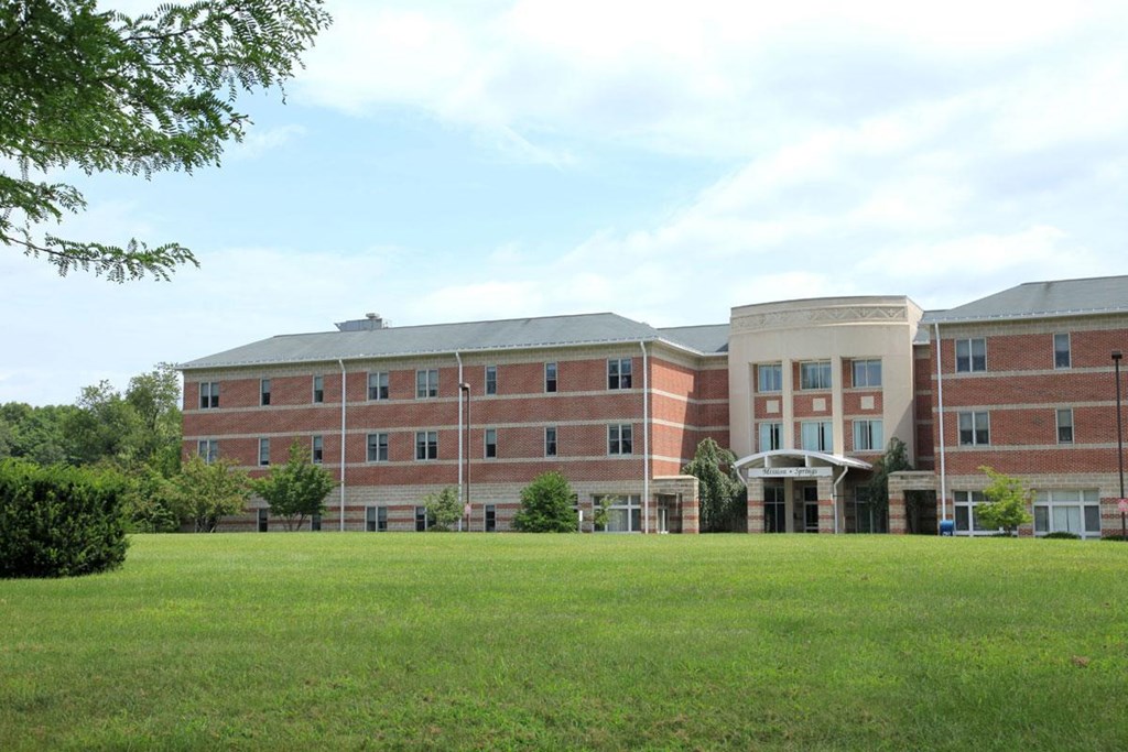a large brick building with a green lawn in front of it