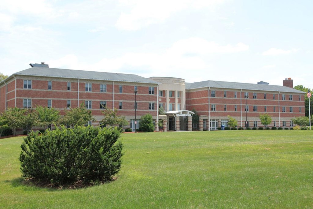 a large brick building with a green field in front of it