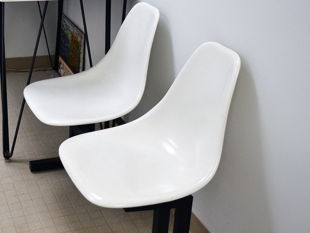 two white chairs sitting next to a white wall