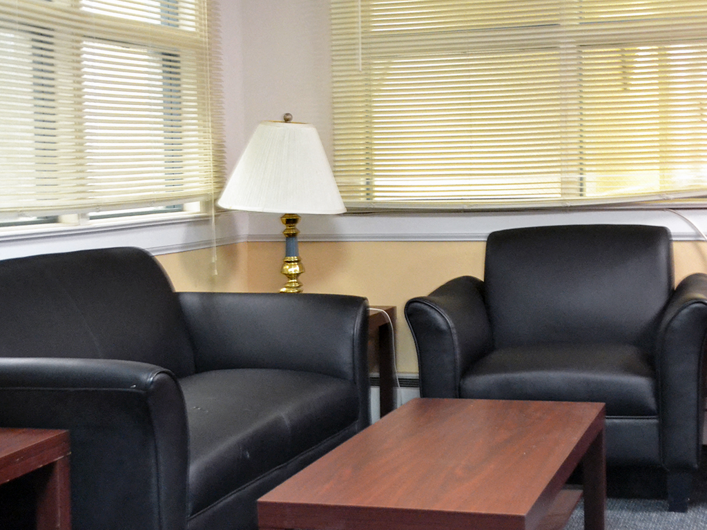a living room with black chairs and a table and a lamp