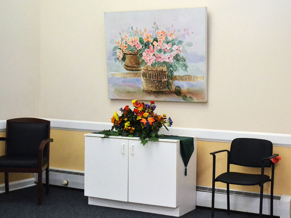 a table with flowers and chairs in a room with a painting