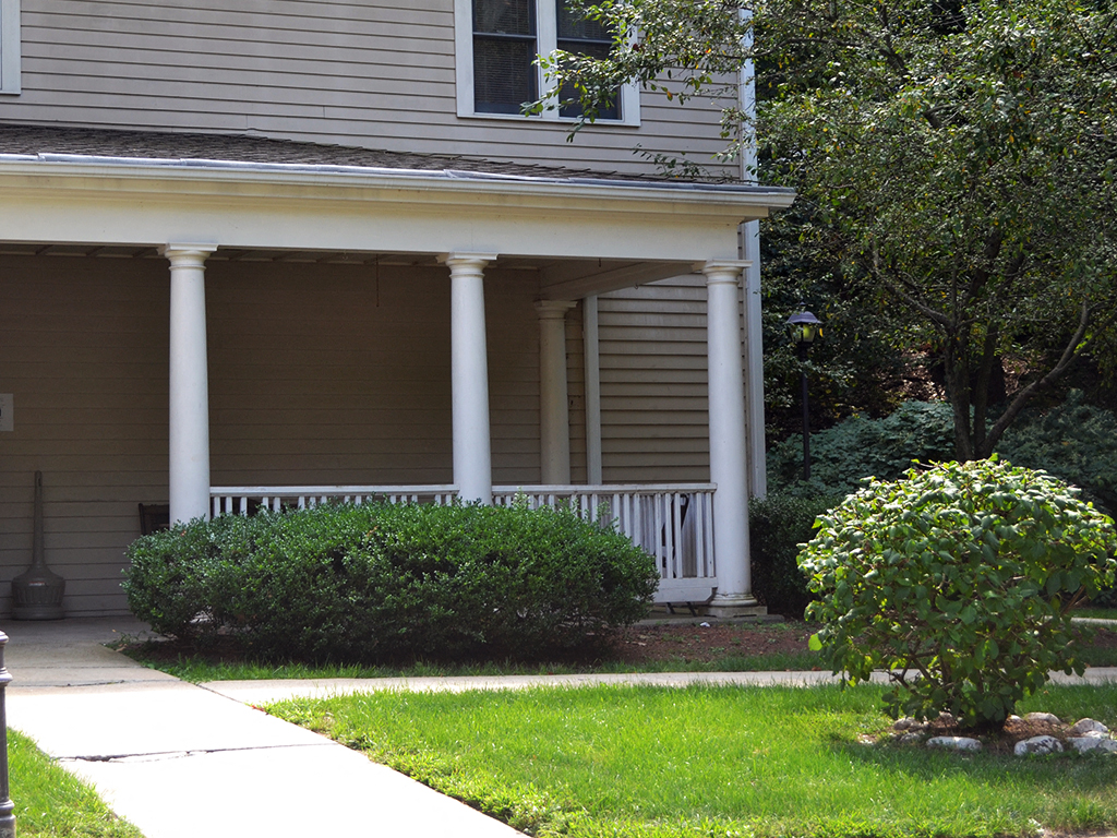 the front of a house with white pillars and a porch