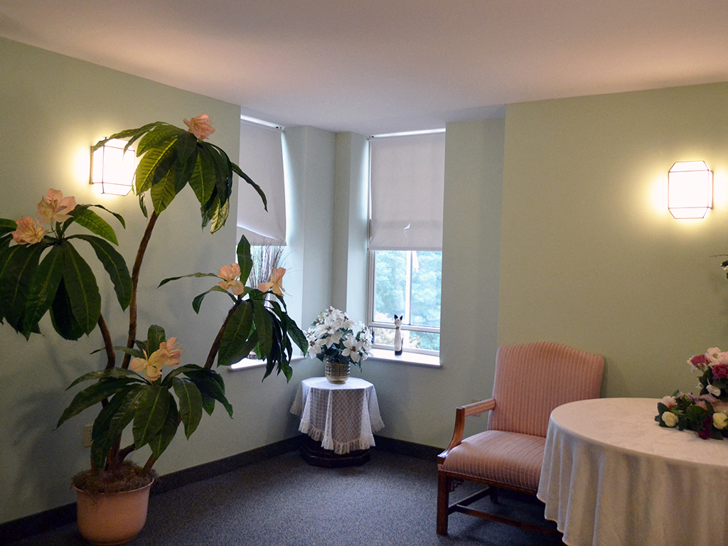 a small room with a table with flowers and a chair