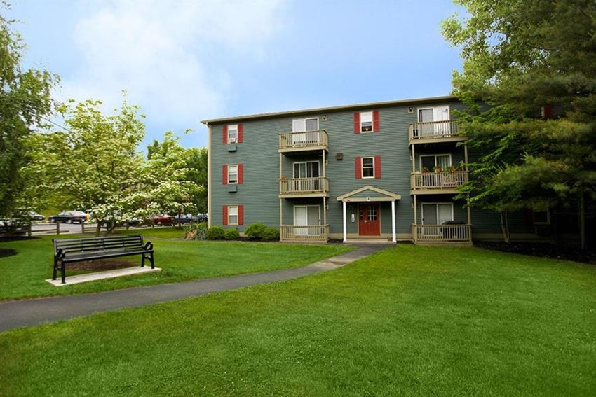 a park bench in front of a green apartment building