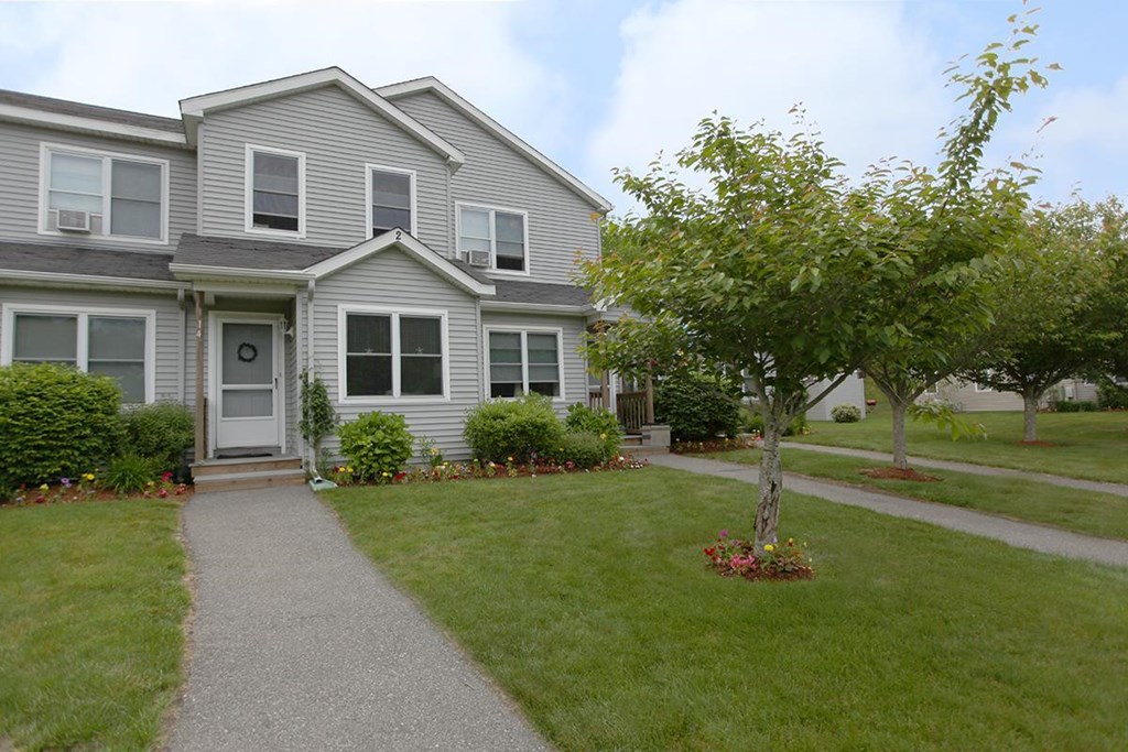the front of a house with a tree in the yard