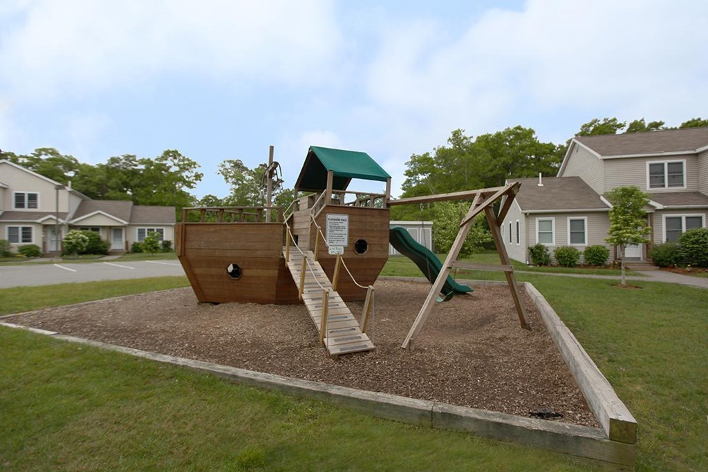 a playground with a pirate ship shaped swing set in a yard