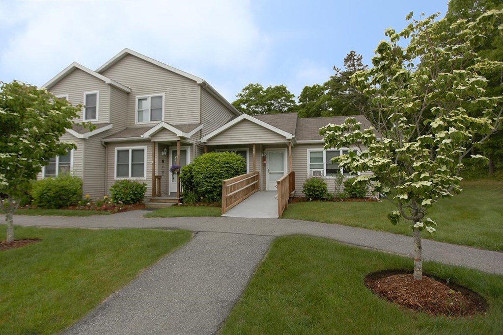 the front of a house with a walkway and a tree