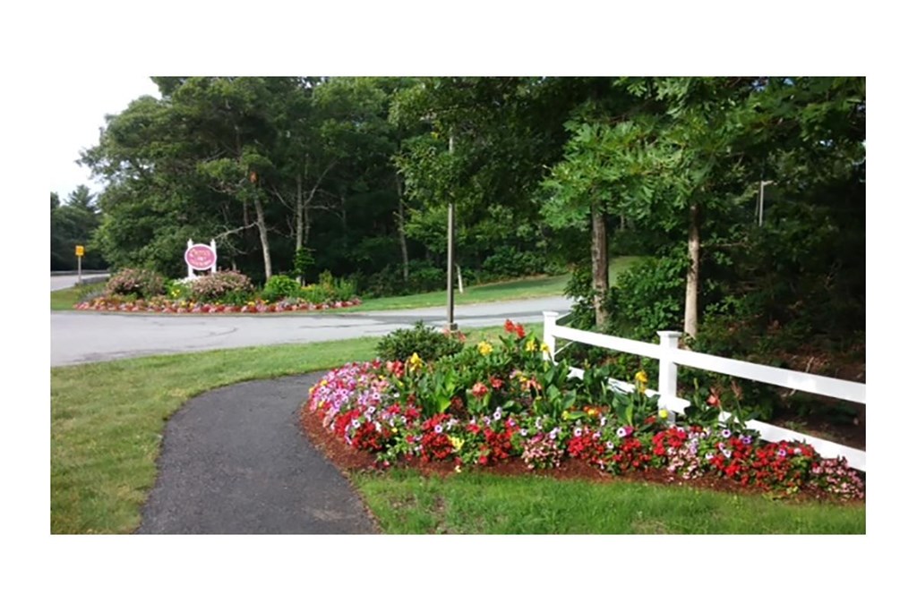 a flower garden in front of a white fence