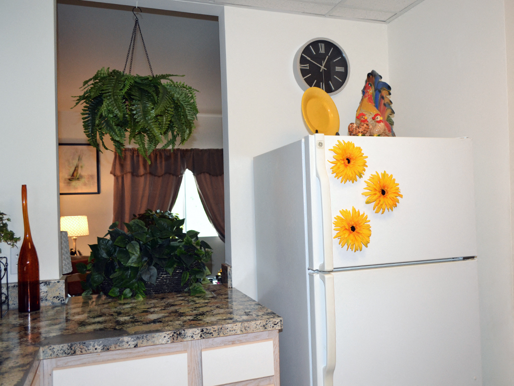 a kitchen with a refrigerator and a counter with sunflowers on it