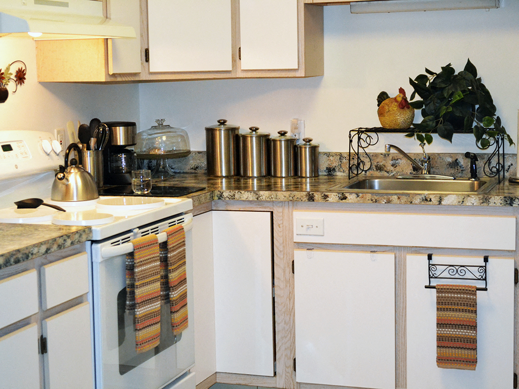 a kitchen with white cabinets and a sink and a counter with pots and pans