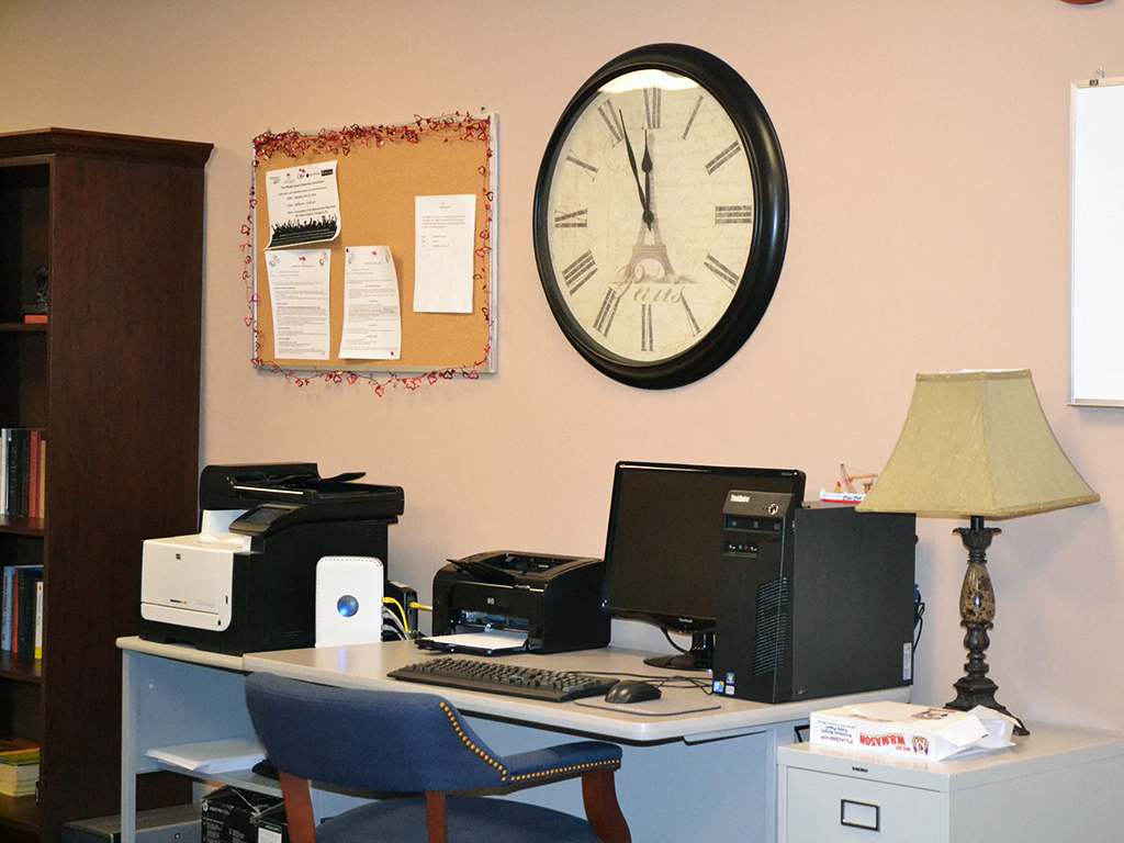 a desk with a computer and a clock on the wall