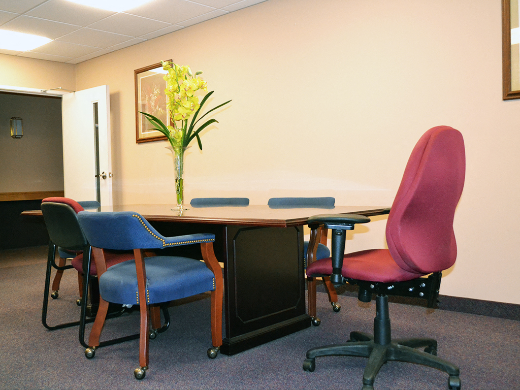 a conference room with a table with chairs and a vase of flowers