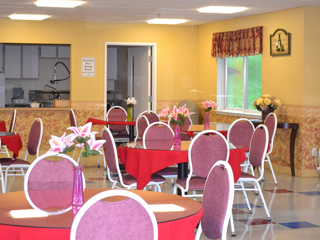 a dining room with tables and chairs and a kitchen in the background