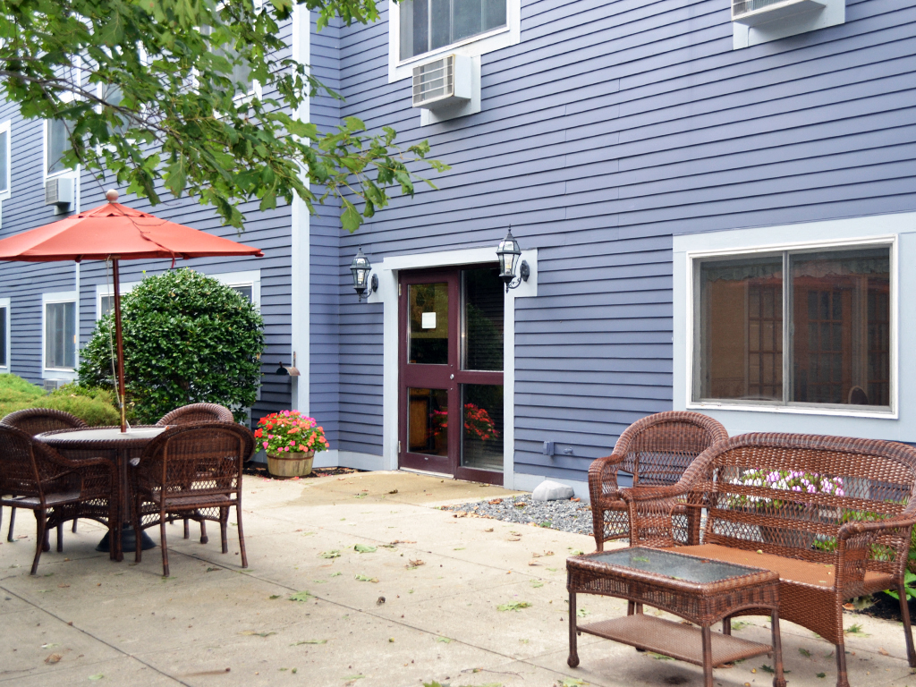 a patio with chairs and an umbrella in front of a blue house