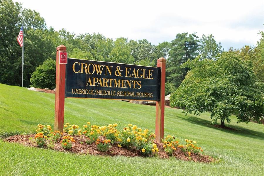 a sign for crown  eagle apartments in a field
