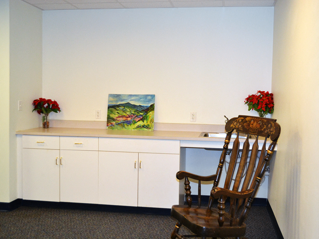 a desk with a chair and a painting in a room