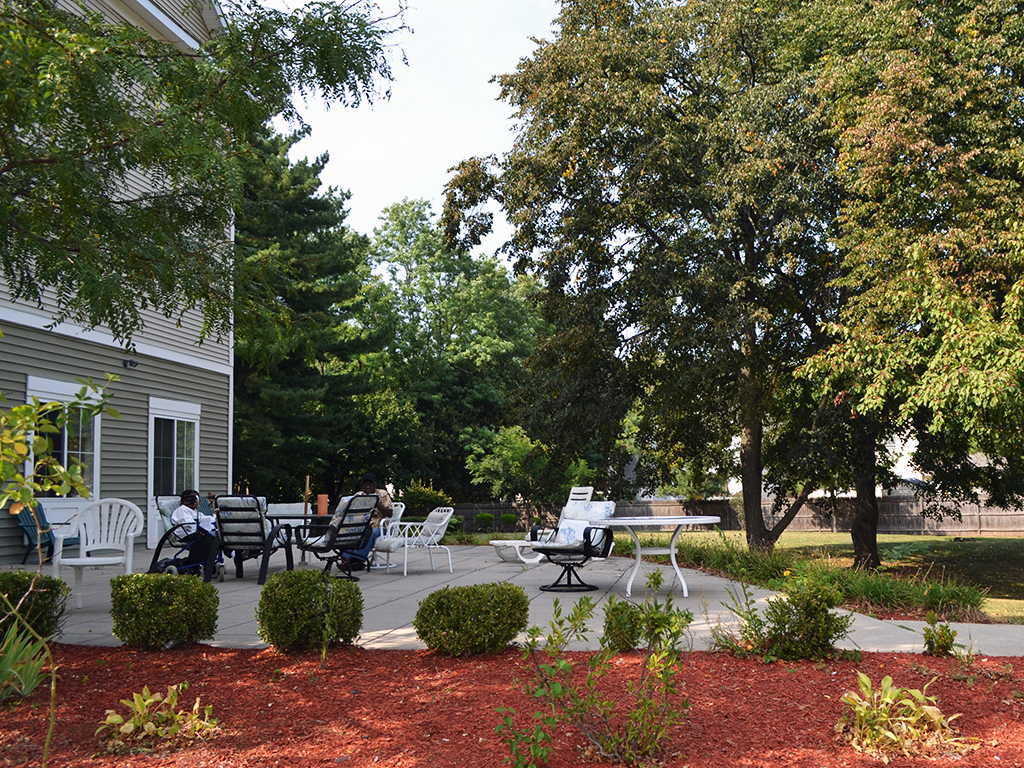 a patio with tables and chairs in front of a house