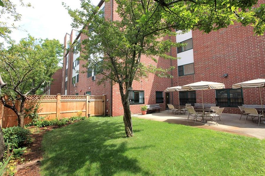 a patio with tables and umbrellas in front of a brick building