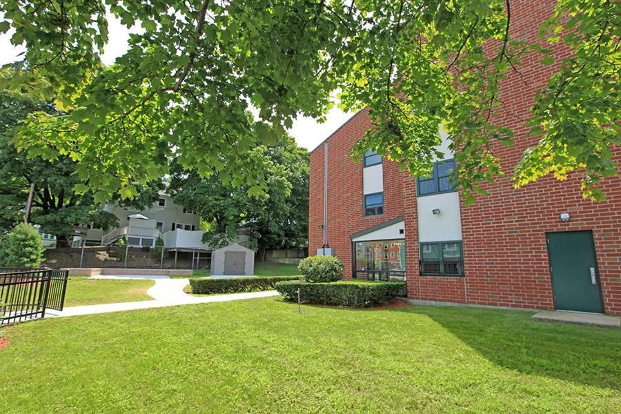 a brick building with a lawn and trees in front of it