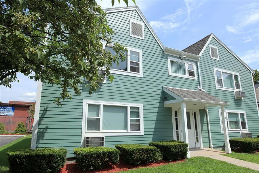 a green house with hedges in front of it