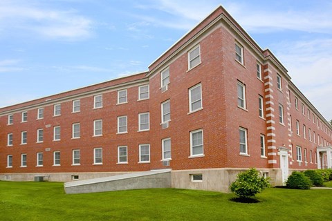 a large brick building with a green lawn