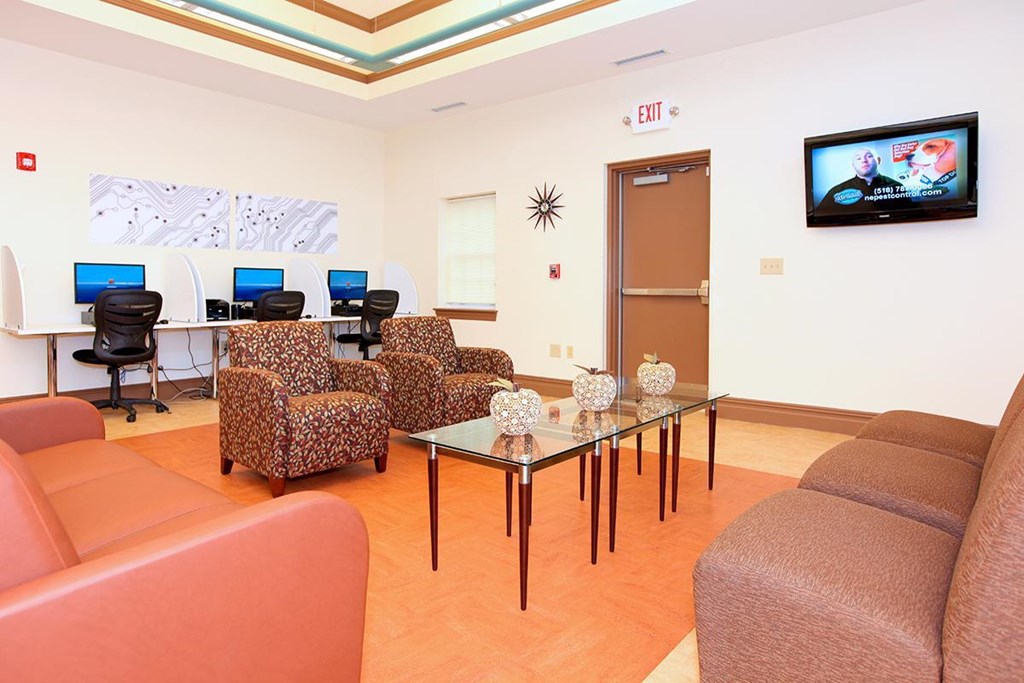 a living room with couches and chairs and a desk with computers