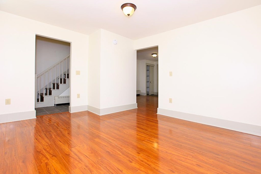 an empty living room with a hard wood floor and a staircase