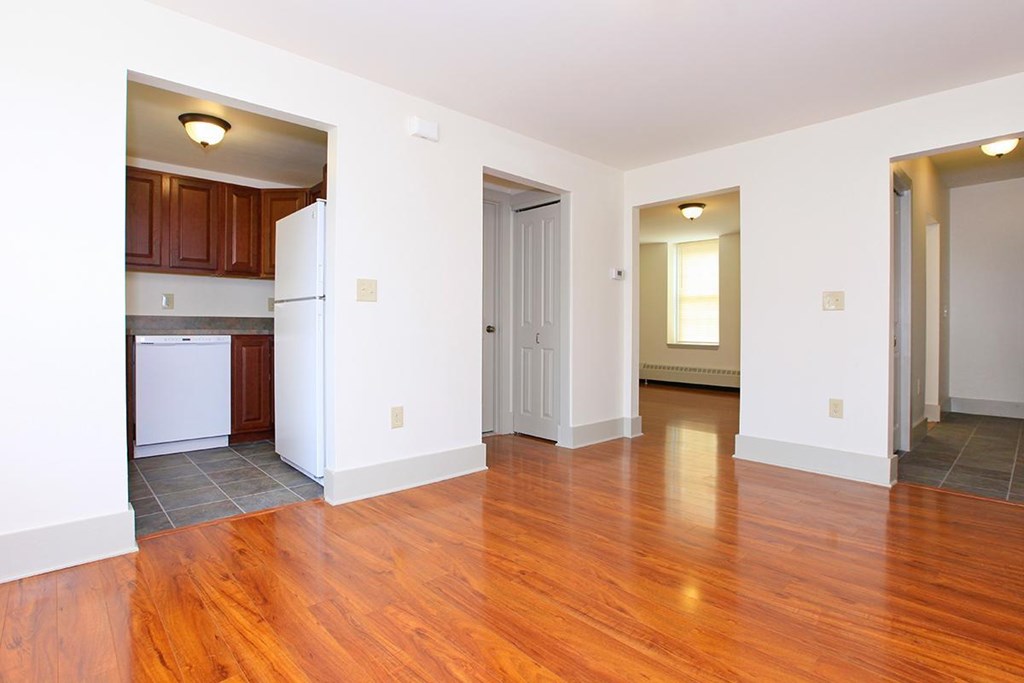 an empty living room and kitchen with wood floors