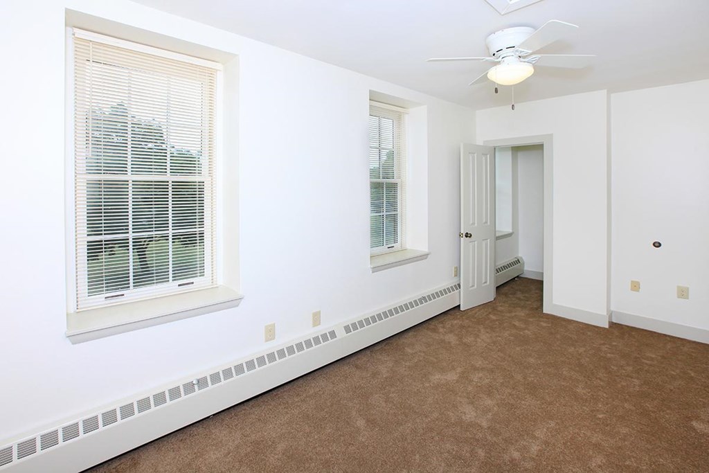 a bedroom with a ceiling fan and two windows