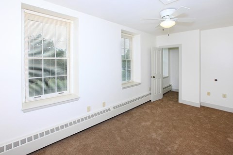 a bedroom with a ceiling fan and two windows