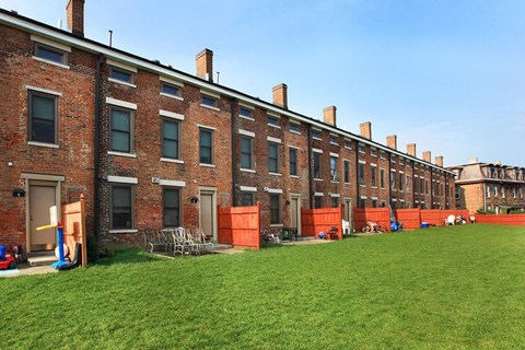 a row of brick buildings with grass in front of them