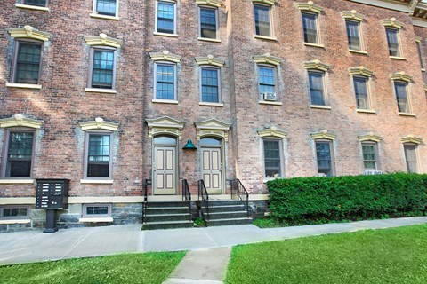 the front of a brick building with steps and a sidewalk