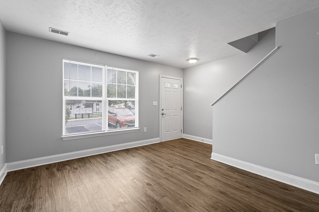 a bedroom with a large window and hardwood floors