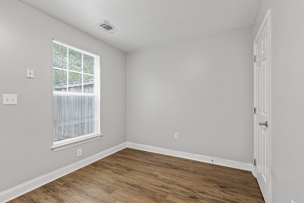 a bedroom with hardwood floors and grey walls