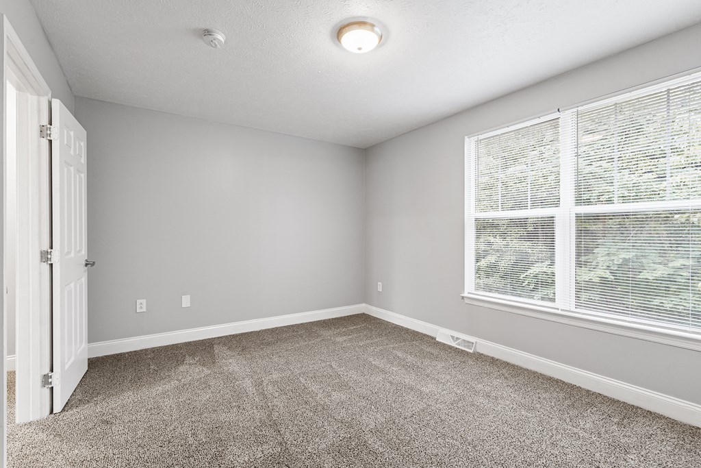 a bedroom with a large window and carpet