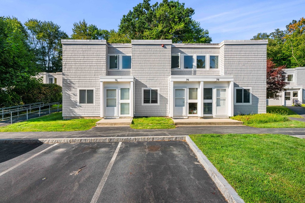 a white house with a parking lot in front of it