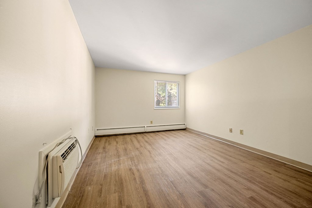 the living room of an empty house with wood flooring and white walls