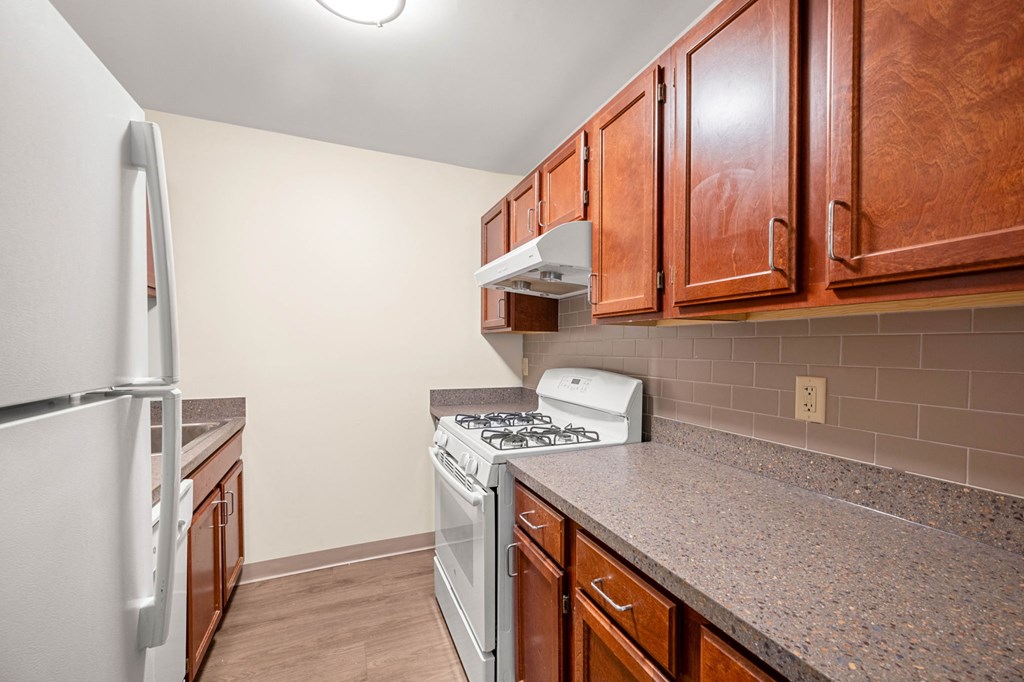 a kitchen with wood cabinets and white appliances and granite counter tops